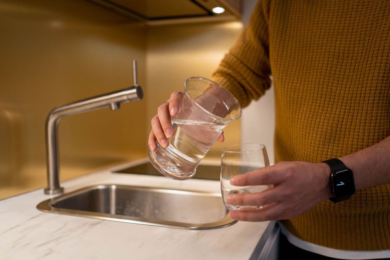 Water wordt uit een karaf in een glas geschonken in een moderne keuken