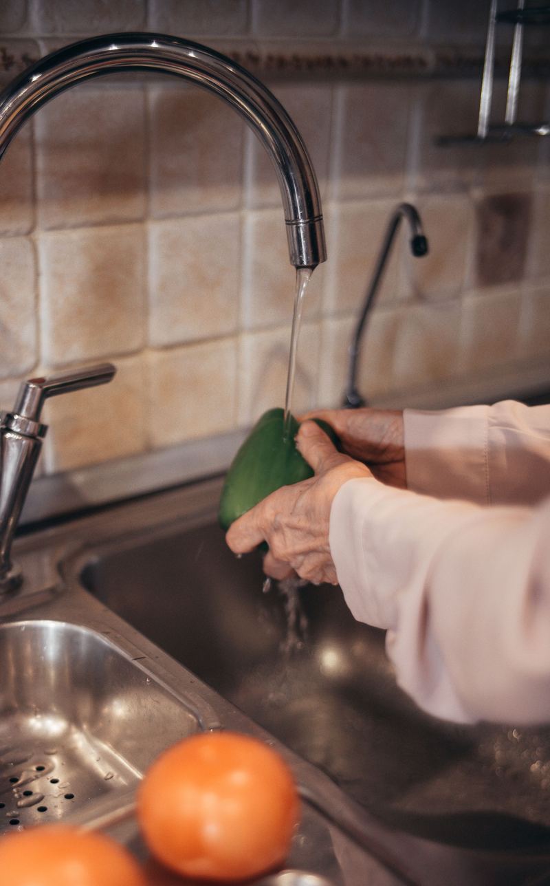 Handen spoelen een paprika af onder de keukenkraan